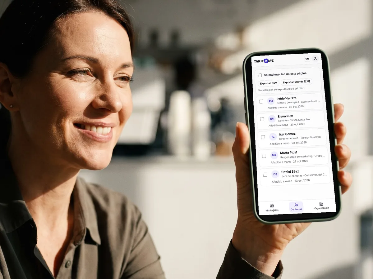 Una mujer sonríe mirando en el móvil la lista de contactos que ha recibido en TARJE2ME